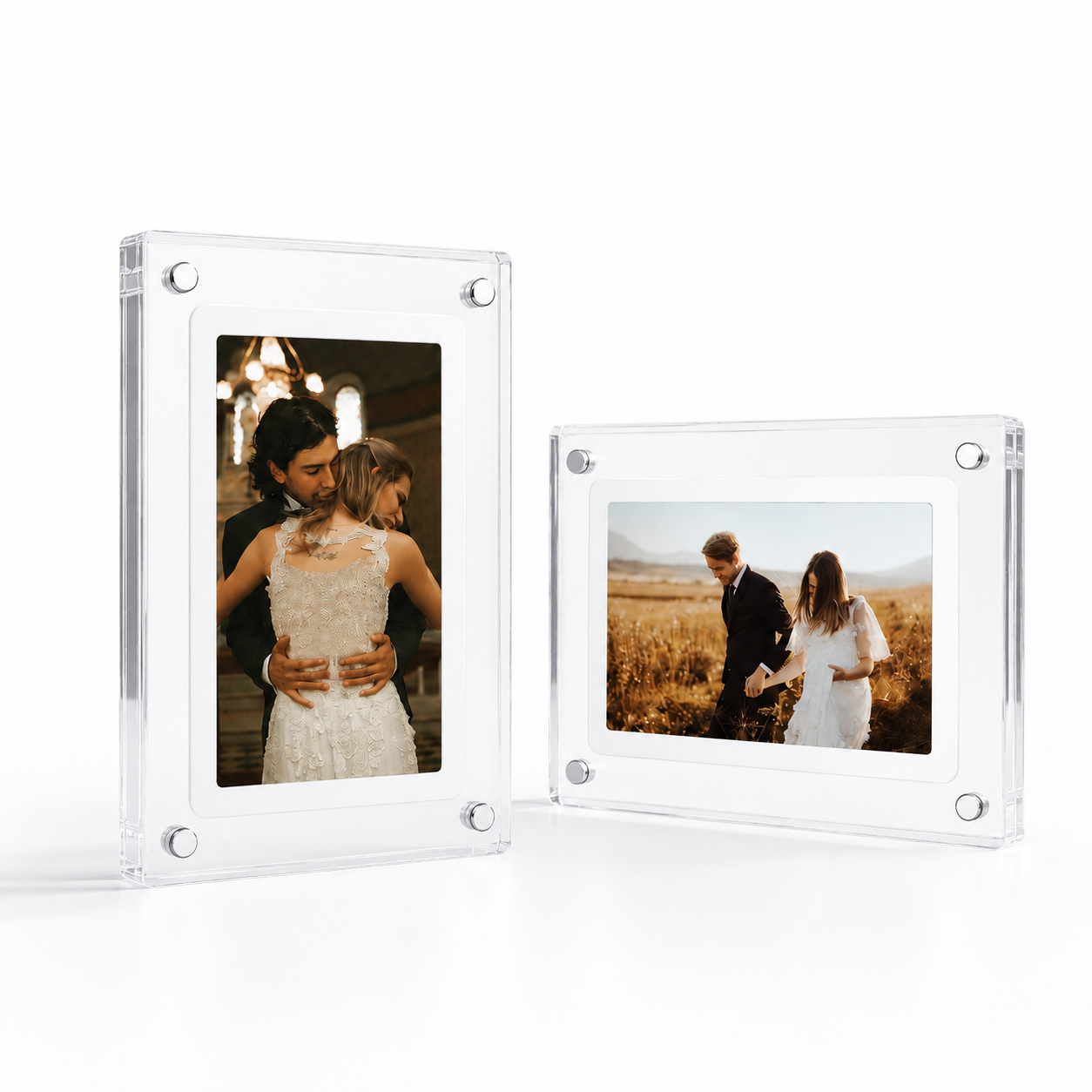 Two clear acrylic Video Picture frames with rounded corners and visible silver corner screws, shown on a white studio background. One frame displays a couple embracing, and the other shows a couple holding hands in a field.